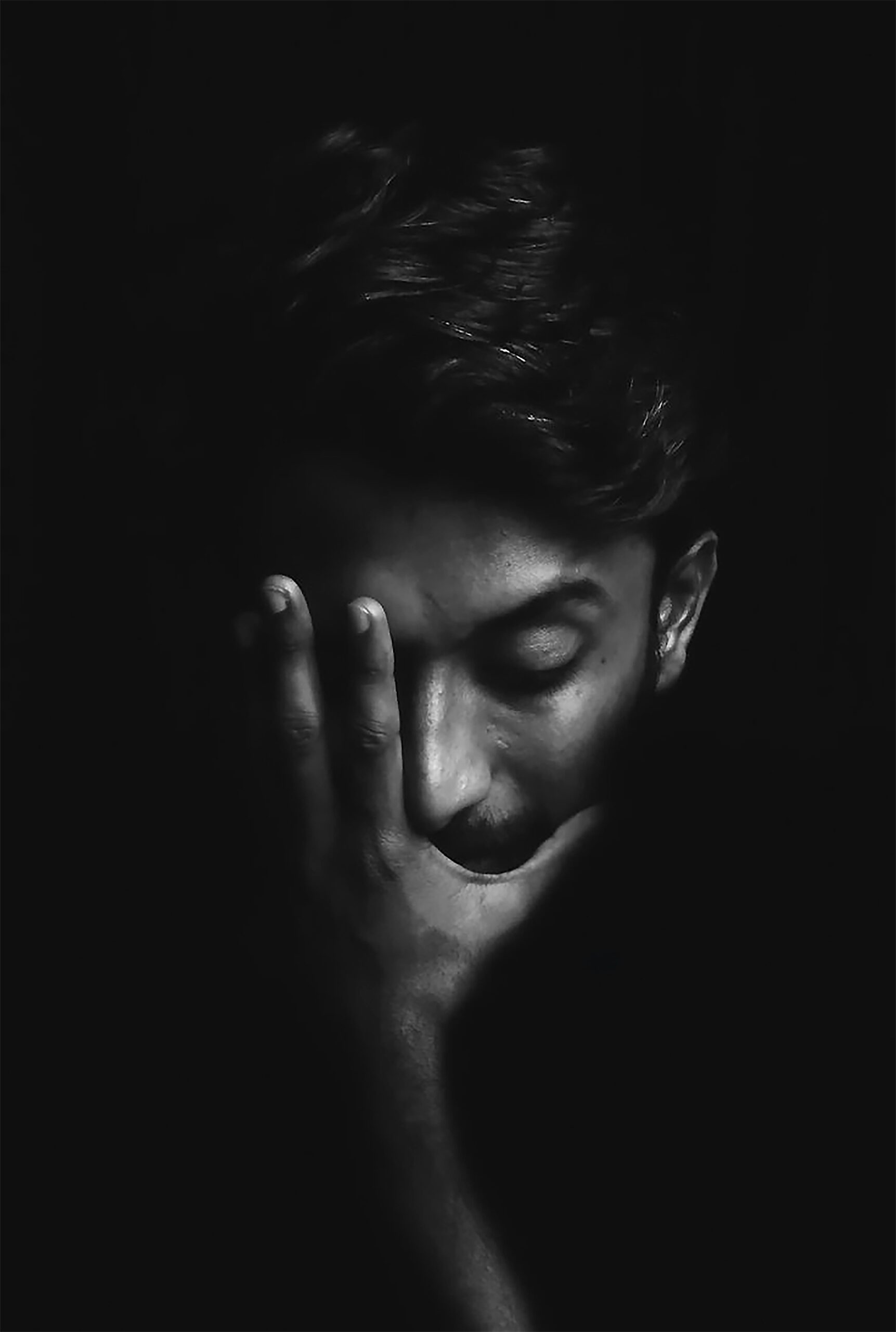 A black and white photo of a person covering their face