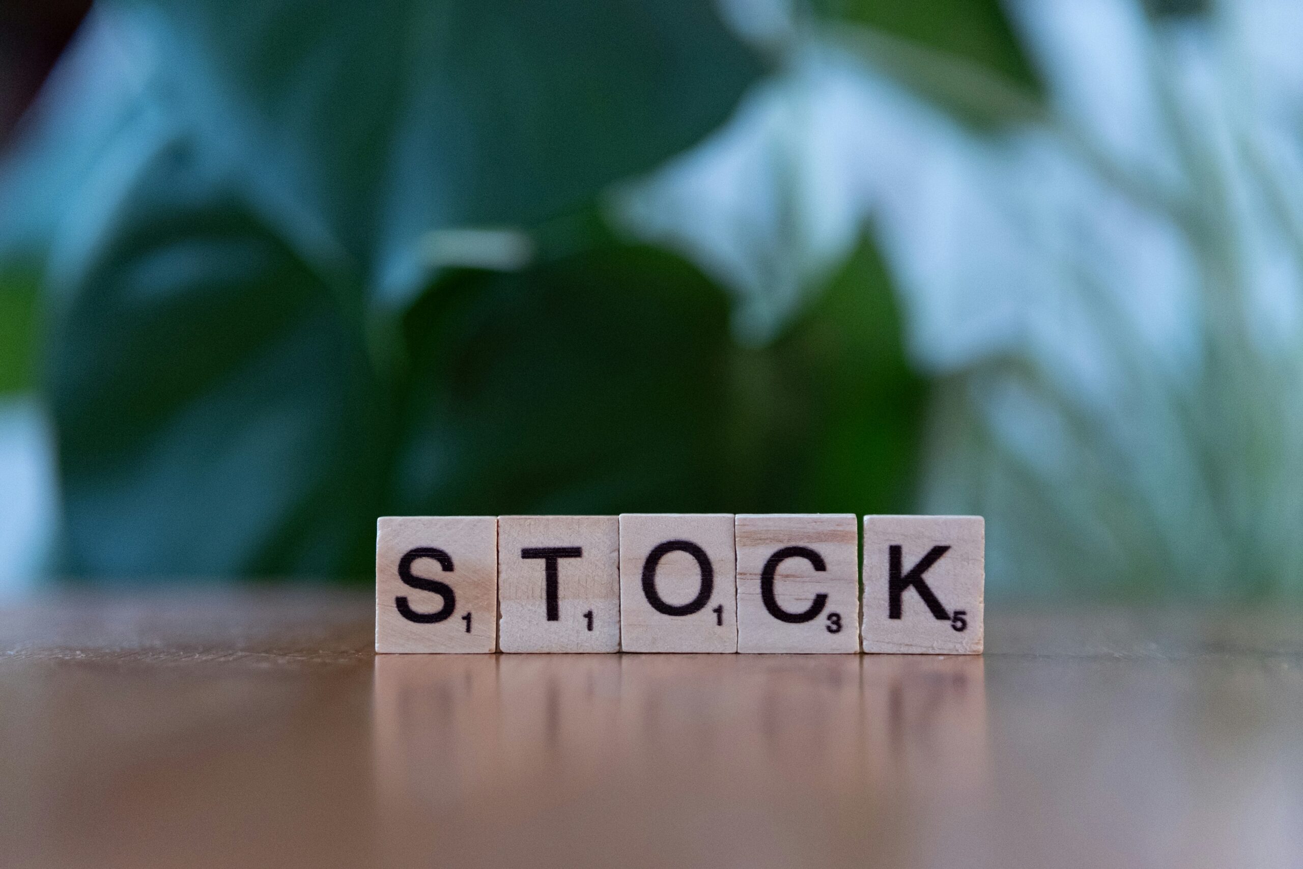A wooden block spelling the word stock on a table