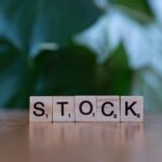 A wooden block spelling the word stock on a table