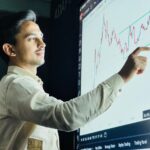Man analyzing stock market graph on a digital board with a focused expression.
